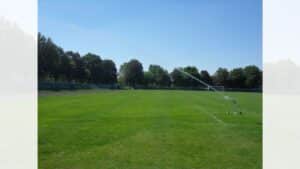 Irrigatore Orma Leader posizionato sul prato verde di uno stadio con tubo srotolato.